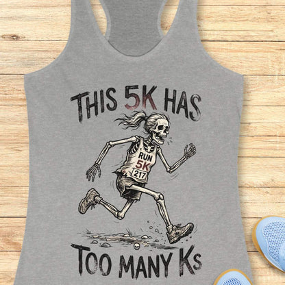 Gray tank top with skeleton running design and text 'This 5k has too many Ks',  on a wooden surface