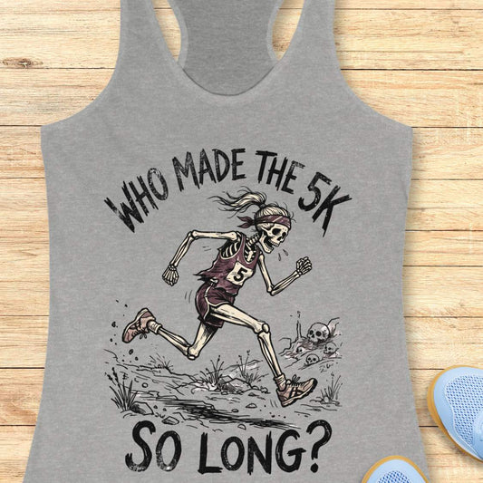 Gray tank top with skeleton running graphic and text 'WHO MADE THE 5K SO LONG?' on a wooden surface.