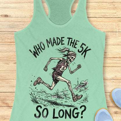Light green tank top with skeleton running graphic and text 'WHO MADE THE 5K SO LONG?' on a wooden surface.