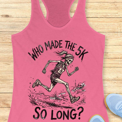 Pink tank top with skeleton running graphic and text 'WHO MADE THE 5K SO LONG?' on a wooden surface.