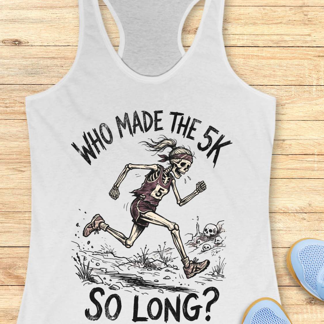 white tank top with skeleton running graphic and text 'WHO MADE THE 5K SO LONG?' on a wooden surface.