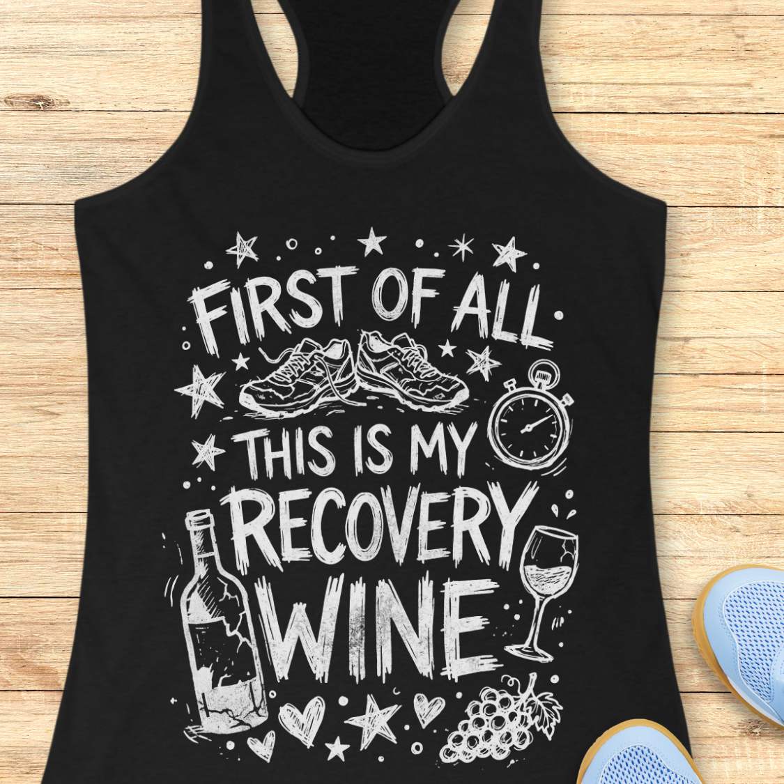 Black tank top with white text 'first of all, this is my recovery wine', and graphics on a wooden surface