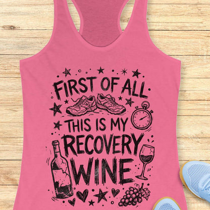 Pink tank top with humorous text 'first of all, this is my recovery wine', and graphics on a wooden surface