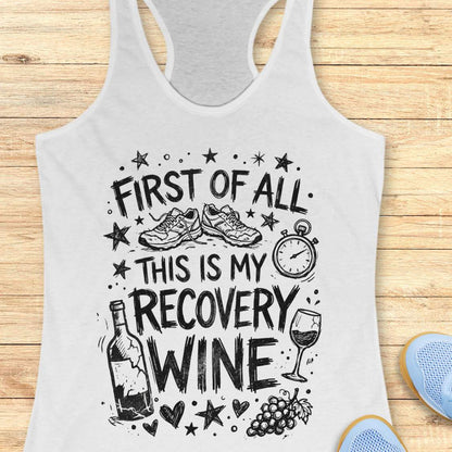 white tank top with 'First of all, this is my recovery wine' text and graphics on a wooden surface.