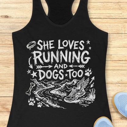 Black tank top with white text 'she loves running and dogs too', and graphics on a wooden surface