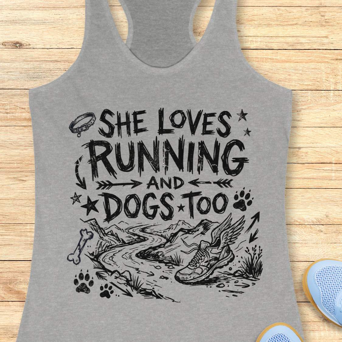 Gray tank top with black text 'she loves running and dogs too', and graphics on a wooden surface