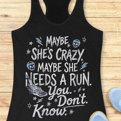 black tank top with black graphic design and text 'maybe she's crazy, maybe she needs a run. you. don't. know.', on a wooden surface