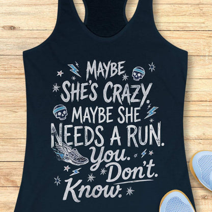 navy tank top with black graphic design and text 'maybe she's crazy, maybe she needs a run. you. don't. know.', on a wooden surface