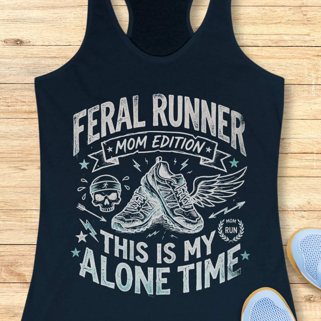 navy tank top with black graphic design and text 'feral runner, mom edition. This is my alone time', on a wooden surface