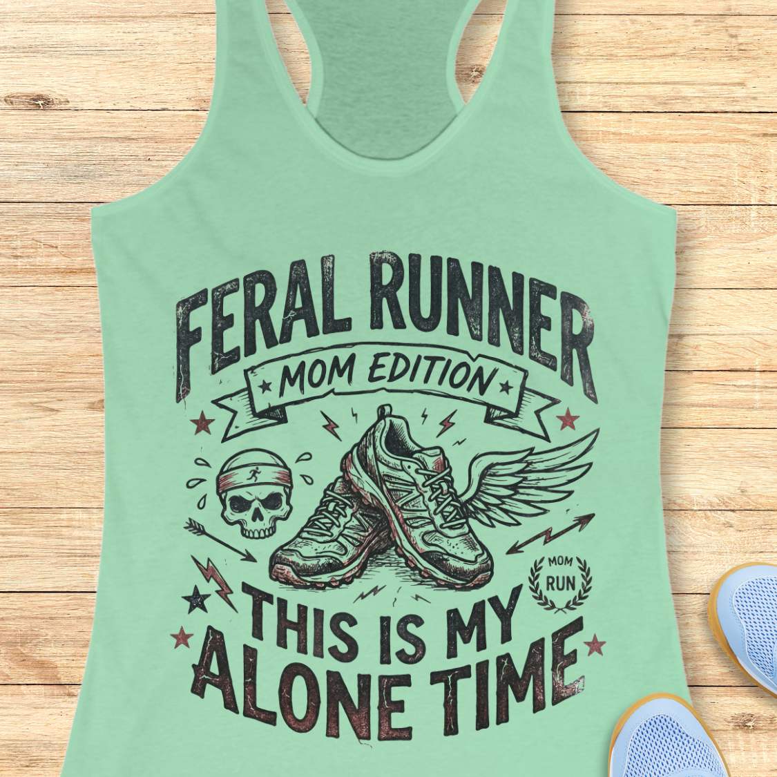 mint tank top with black graphic design and text 'feral runner, mom edition. This is my alone time', on a wooden surface