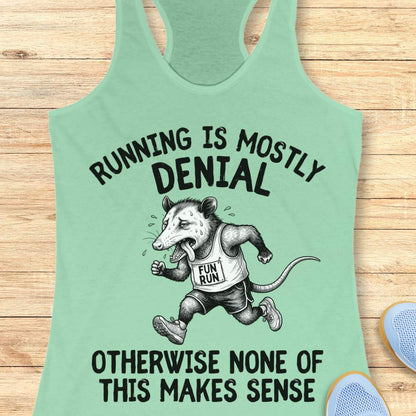 mint tank top with black graphic design and text 'running is mostly denial. otherwise, none of this makes sense.', on a wooden surface