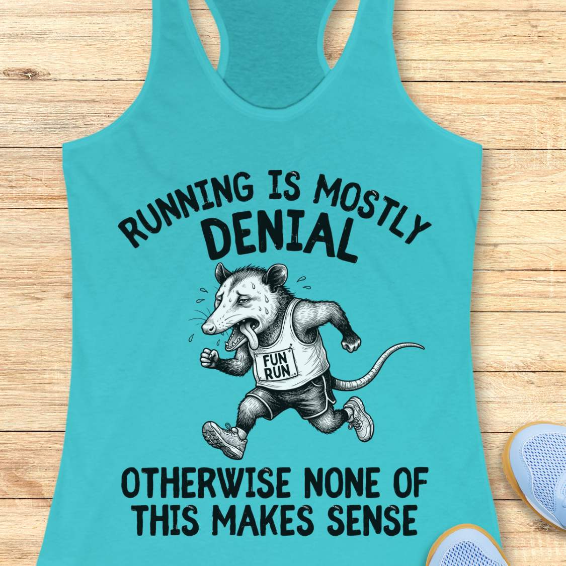 blue tank top with black graphic design and text 'running is mostly denial. otherwise, none of this makes sense.', on a wooden surface