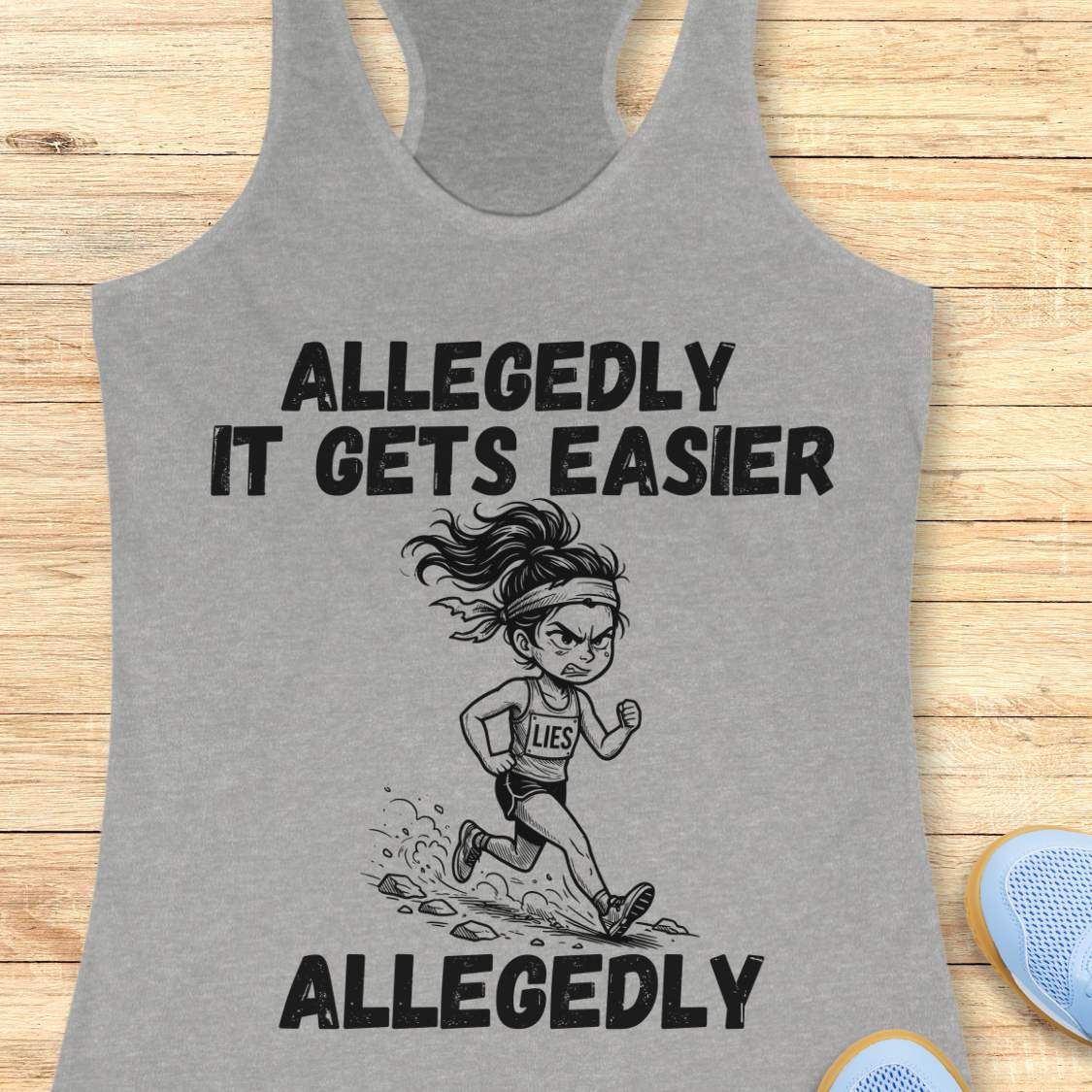 grey tank top with black graphic design and text 'allegedly it gets easier. Allegedly.', on a wooden surface