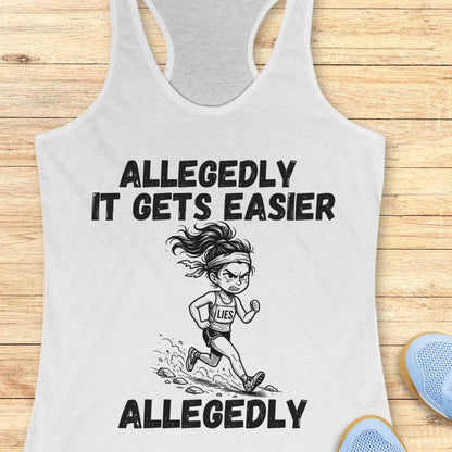 white tank top with black graphic design and text 'allegedly it gets easier. Allegedly.', on a wooden surface