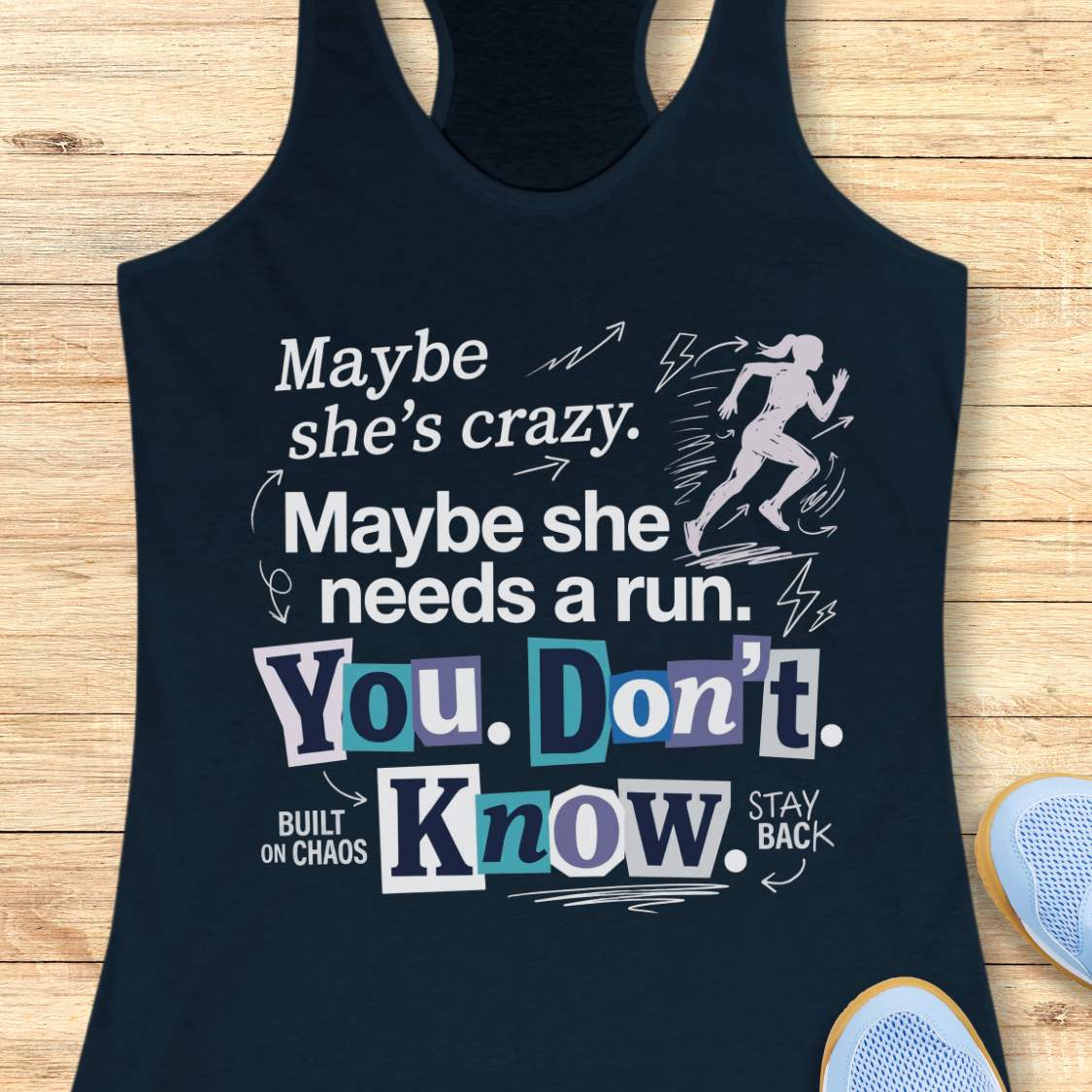 navy tank top with graphic design and text 'Maybe she's crazy. Maybe she needs a run. You. Don't. Know.', on a wooden surface