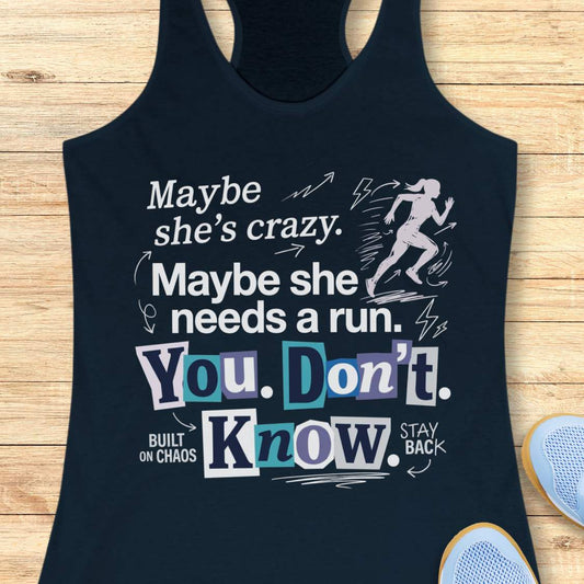 navy tank top with graphic design and text 'Maybe she's crazy. Maybe she needs a run. You. Don't. Know.', on a wooden surface
