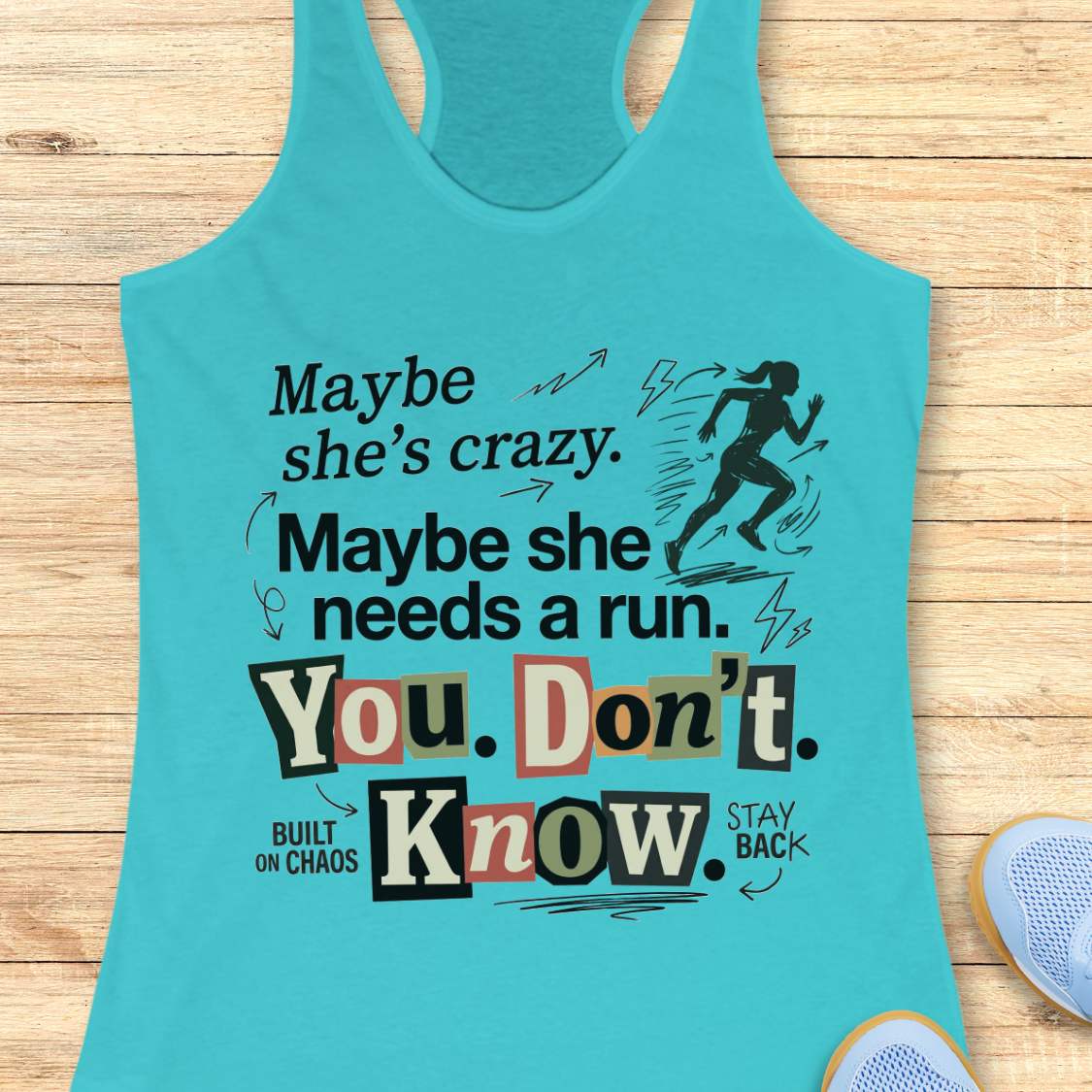 blue tank top with graphic design and text 'Maybe she's crazy. Maybe she needs a run. You. Don't. Know.', on a wooden surface