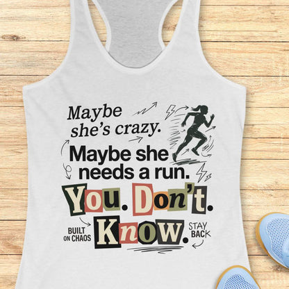 white tank top with graphic design and text 'Maybe she's crazy. Maybe she needs a run. You. Don't. Know.', on a wooden surface