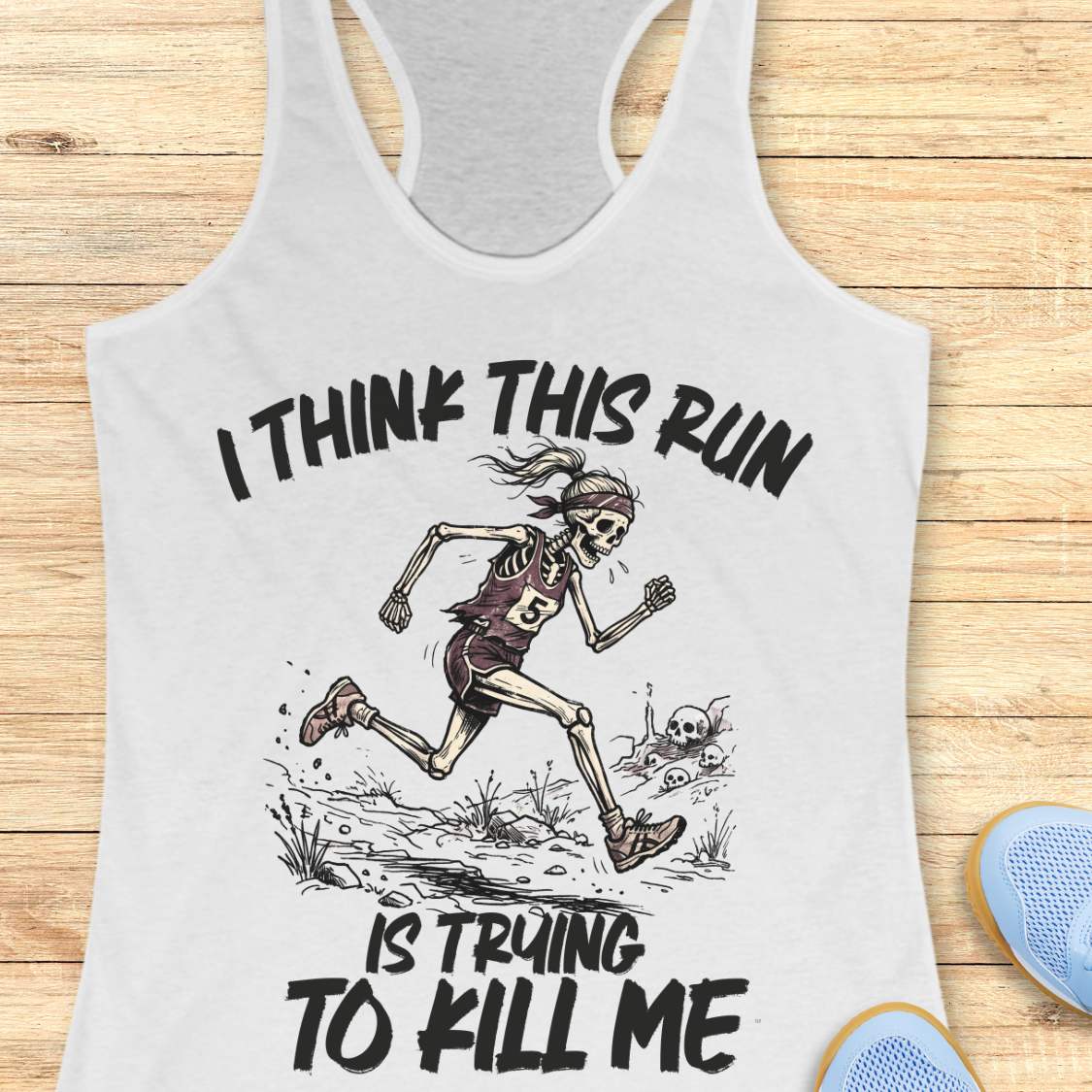 white tank top with graphic design of a runner skeleton and text 'I think this run is trying to kill me', on a wooden surface