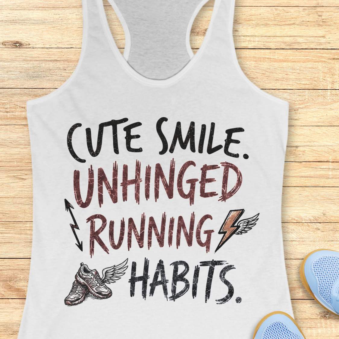 white tank top with text 'cute smile unhinged running habits', on a wooden surface