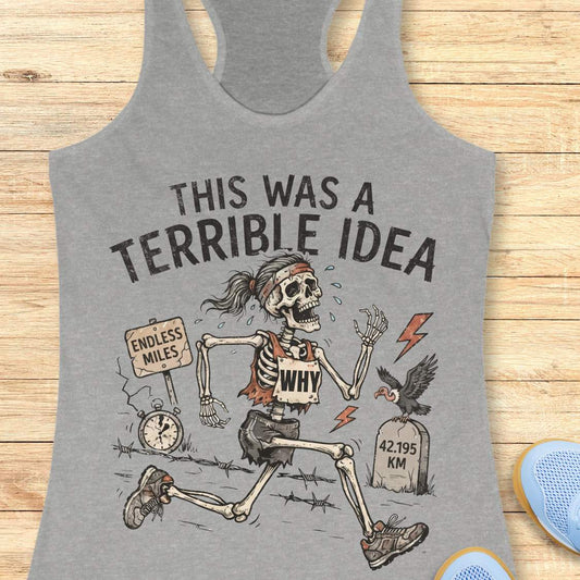 grey tank top with a running skeleton and text 'This was a terrible idea', on a wooden surface