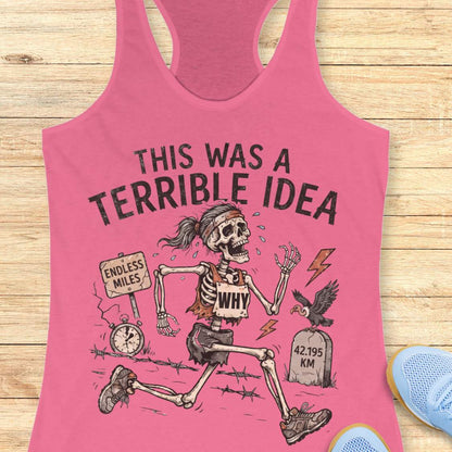 pink tank top with a running skeleton and text 'This was a terrible idea', on a wooden surface