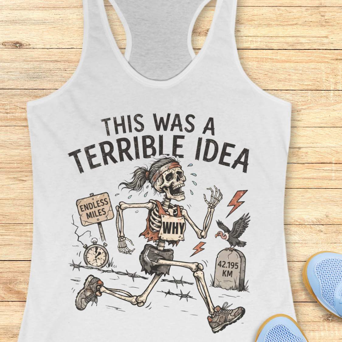 white tank top with a running skeleton and text 'This was a terrible idea', on a wooden surface
