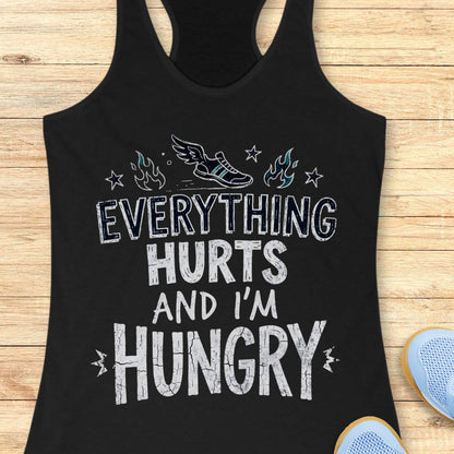 black tank top with text 'everything hurts and I'm hungry', on a wooden surface