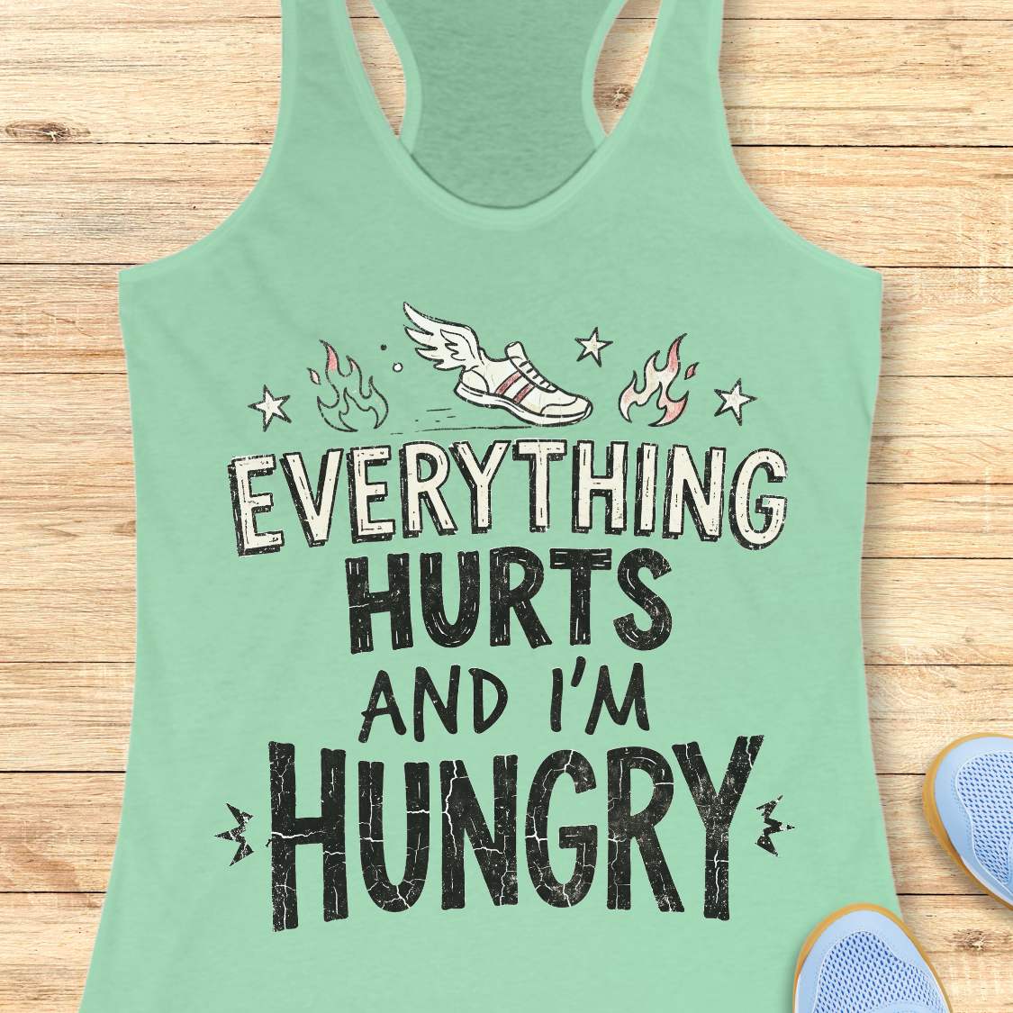 mint tank top with text 'everything hurts and I'm hungry', on a wooden surface