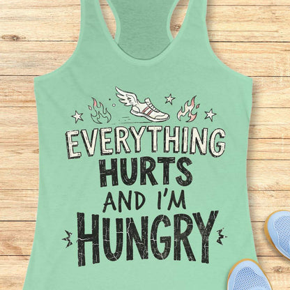 mint tank top with text 'everything hurts and I'm hungry', on a wooden surface