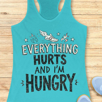 blue tank top with text 'everything hurts and I'm hungry', on a wooden surface