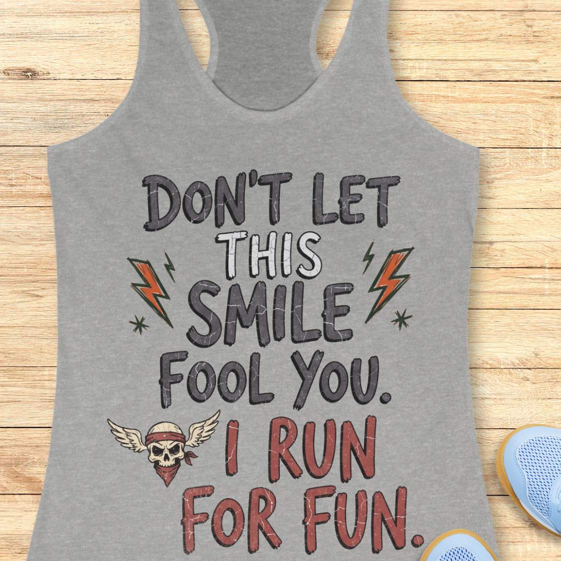 grey tank top with text 'Don't let this smile fool you. I run for fun', on a wooden surface