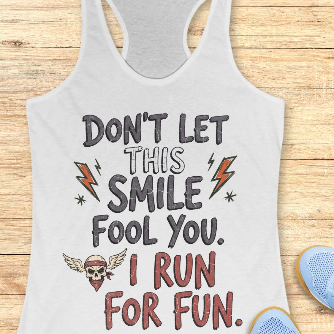 white tank top with text 'Don't let this smile fool you. I run for fun', on a wooden surface