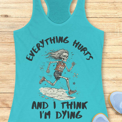 A blue racerback tank top laid flat on a light wood background, featuring a humorous skeleton runner graphic with the text 'everything hurts and I think I'm dying'.