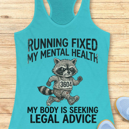 A turquoise racerback tank top laid flat on a light wood surface, featuring a black graphic of a raccoon running with the text 'RUNNING FIXED MY MENTAL HEALTH MY BODY IS SEEKING LEGAL ADVICE'. A partial light blue shoe is visible at the bottom right.