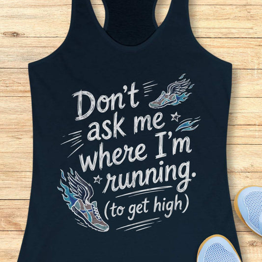 A navy racerback tank top laid flat on a light wood background, featuring a white graphic text print that reads 'Don't ask me where I'm running. (to get high)' with stylized running shoe illustrations in blue, gray, and white.