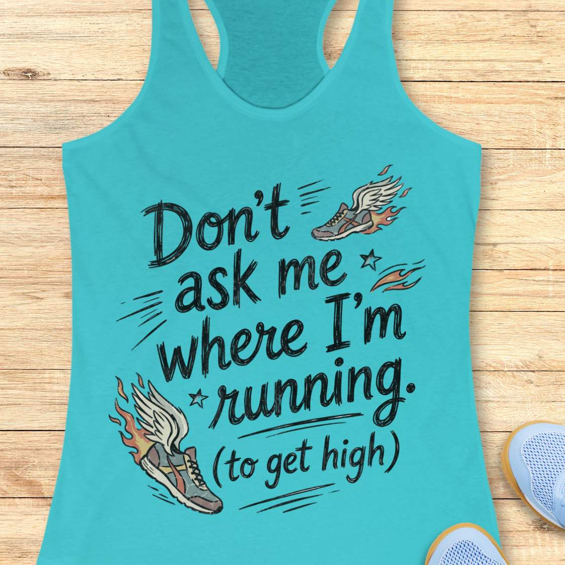 A turquoise racerback tank top laid flat on a light wood surface, featuring a black graphic text that reads 'Don't ask me where I'm running. (to get high)' with illustrated winged running shoes and small flame accents.