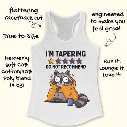 A white racerback tank top with a humorous raccoon graphic and the text 'I'M TAPERING DO NOT RECOMMEND' on a light cream background, surrounded by decorative hand-written text callouts.