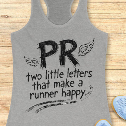 A heather gray racerback tank top with a black graphic print reading 'PR two little letters that make a runner happy' with wings and track lines, shown on a light wood background with partial blue shoes at the corner.