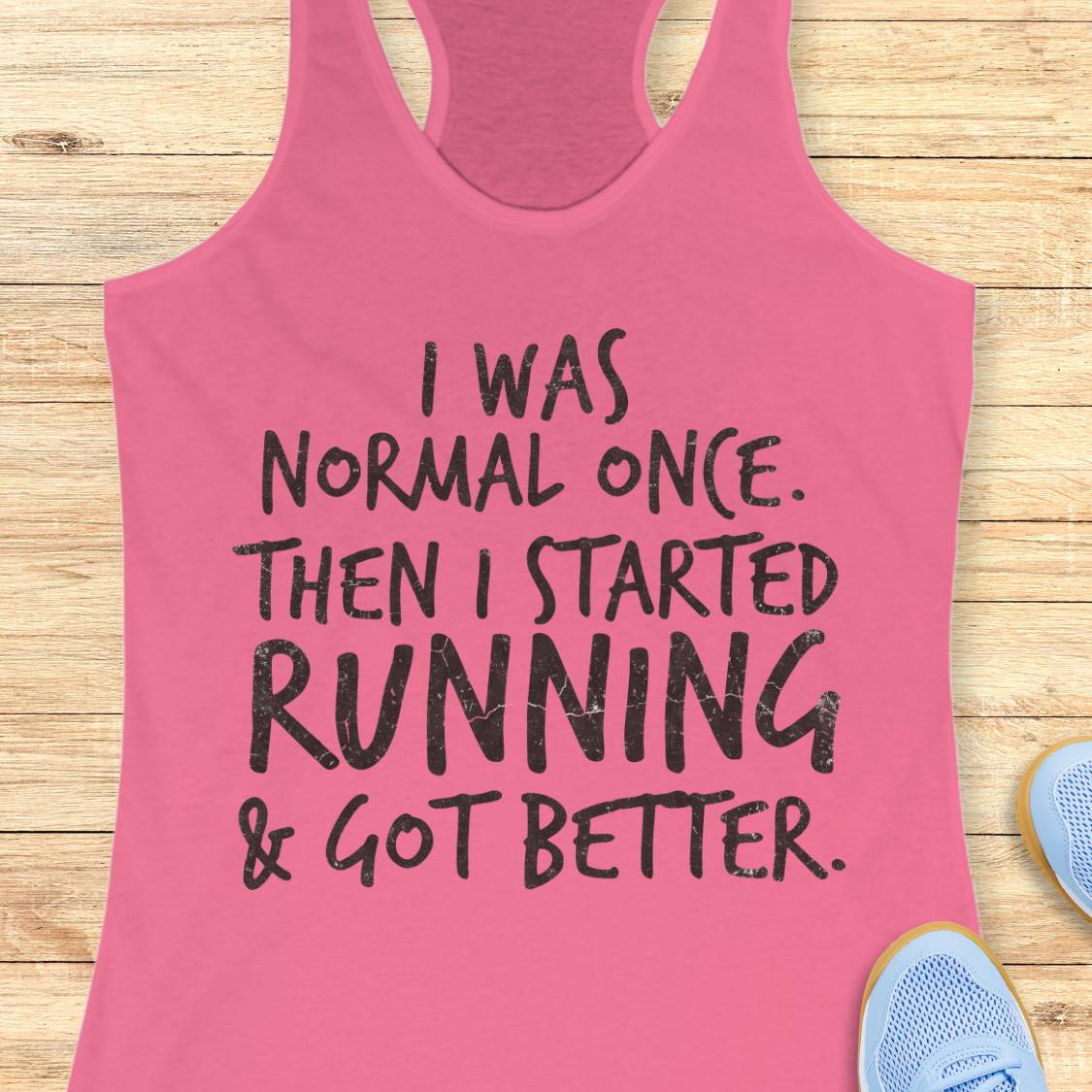 A pink racerback tank top with black distressed text reading 'I WAS NORMAL ONCE. THEN I STARTED RUNNING & GOT BETTER.