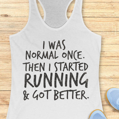 A white racerback tank top with black text reading 'I WAS NORMAL ONCE. THEN I STARTED RUNNING & GOT BETTER.