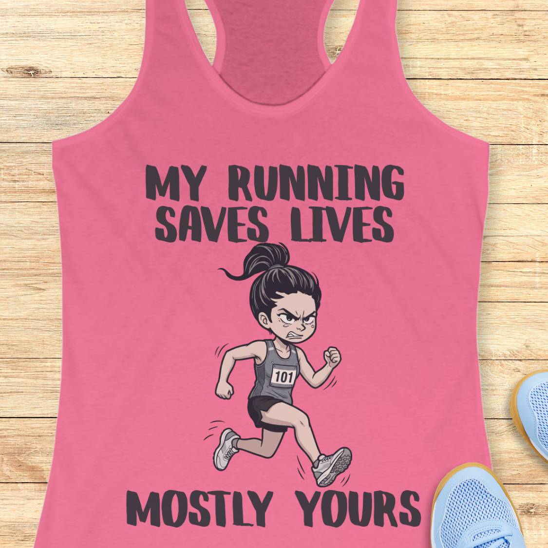 A pink racerback tank top laid flat on a light wood background, featuring a cartoon illustration of a running woman and the text 'MY RUNNING SAVES LIVES MOSTLY YOURS.' Partial blue sneakers appear at the lower right as styling props.