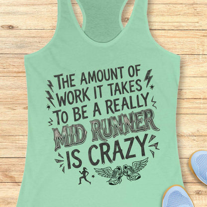 A mint green racerback tank top with a humorous graphic for mid-runners, laid flat on a light wood background with athletic shoes partially visible in the corner.