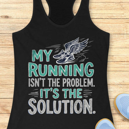 A black racerback tank top laid flat on a light wood background, featuring a graphic print that reads 'MY RUNNING ISN'T THE PROBLEM. IT'S THE SOLUTION.
