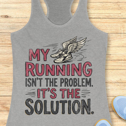 A heather gray racerback tank top laid flat on a light wood background, featuring a graphic print with the text 'MY RUNNING ISN'T THE PROBLEM. IT'S THE SOLUTION.