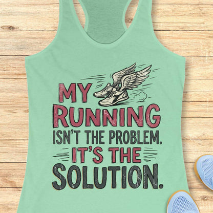 A mint green racerback tank top laid flat on a light wood background, featuring a graphic print of winged running shoes and the text 'MY RUNNING ISN'T THE PROBLEM. IT'S THE SOLUTION.