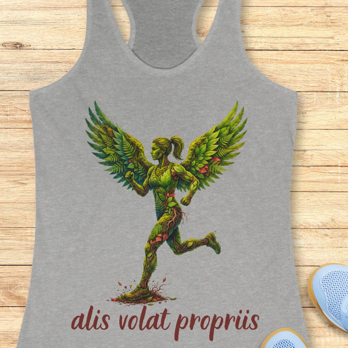 A heather gray racerback tank top featuring a graphic of a winged female figure made of green vines and leaves, with the text 'alis volat propriis' printed below in dark red. The tank top is displayed flat on a light wood background with a pair of blue sneakers partially visible at the bottom right.