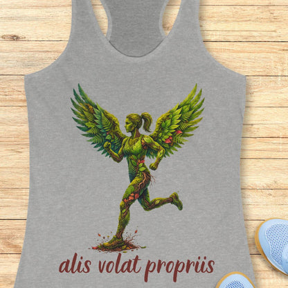 A heather gray racerback tank top featuring a graphic of a winged female figure made of green vines and leaves, with the text 'alis volat propriis' printed below in dark red. The tank top is displayed flat on a light wood background with a pair of blue sneakers partially visible at the bottom right.
