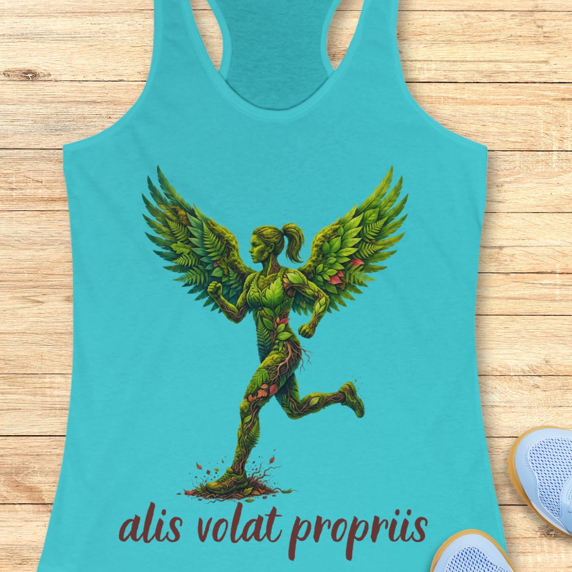 A turquoise racerback tank top laid flat on a light wood background, featuring a green winged female figure graphic and the text 'alis volat propriis' in dark red script near the hem.