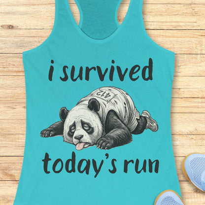 A turquoise racerback tank top laid flat on a light wood surface, featuring a printed graphic of a panda wearing a race bib and the text 'i survived today's run'. Partial blue shoes are visible at the bottom right edge.